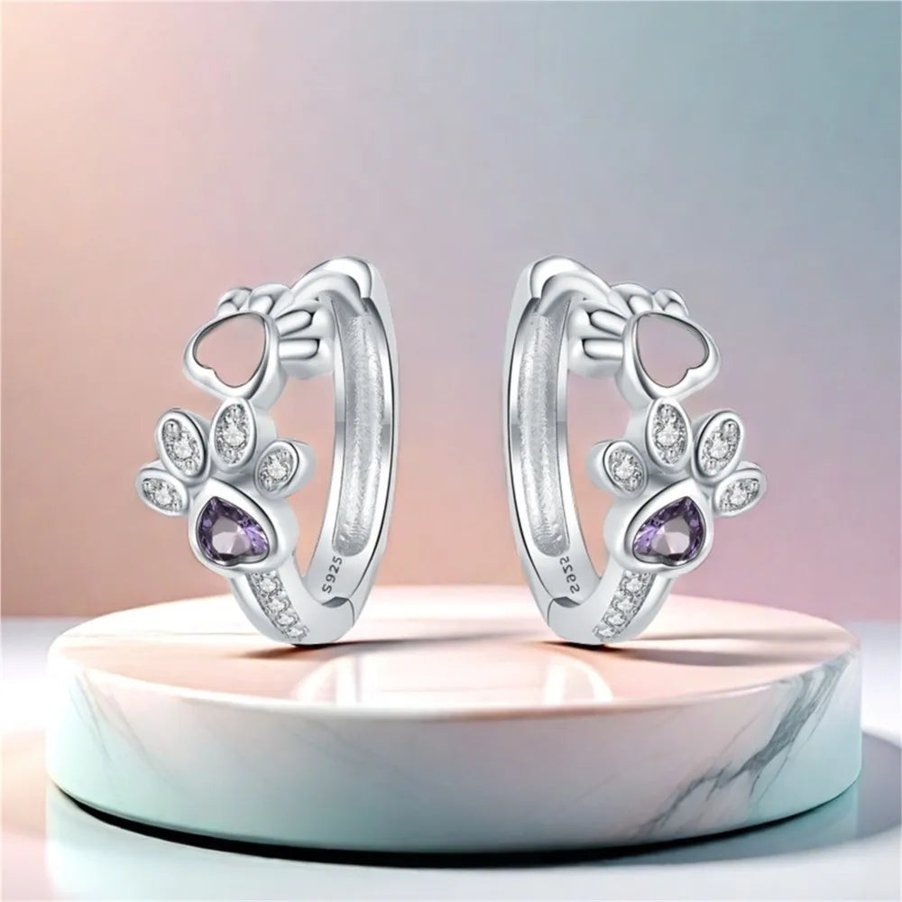 Silver earrings with paw print, zirconia, and a heart-shaped gemstone.