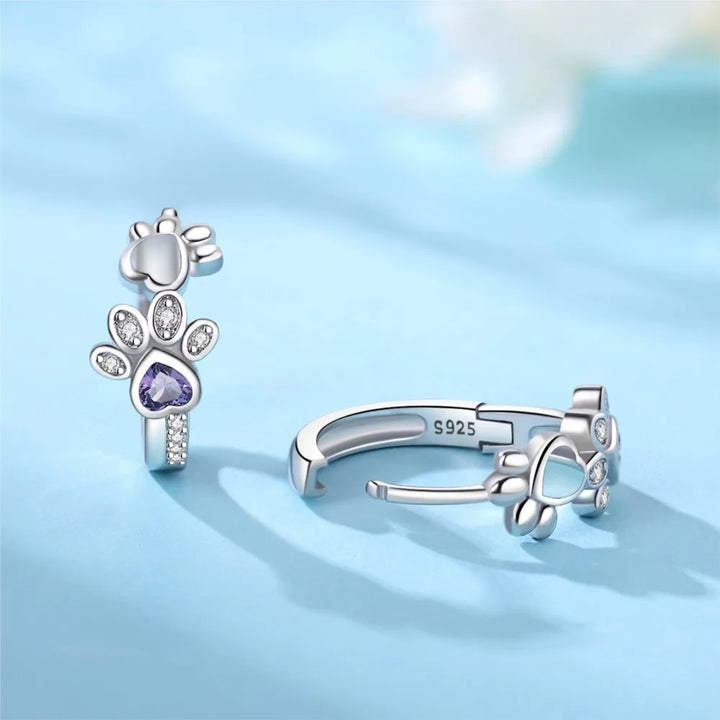 Silver earrings with paw print, zirconia, and a heart-shaped gemstone.